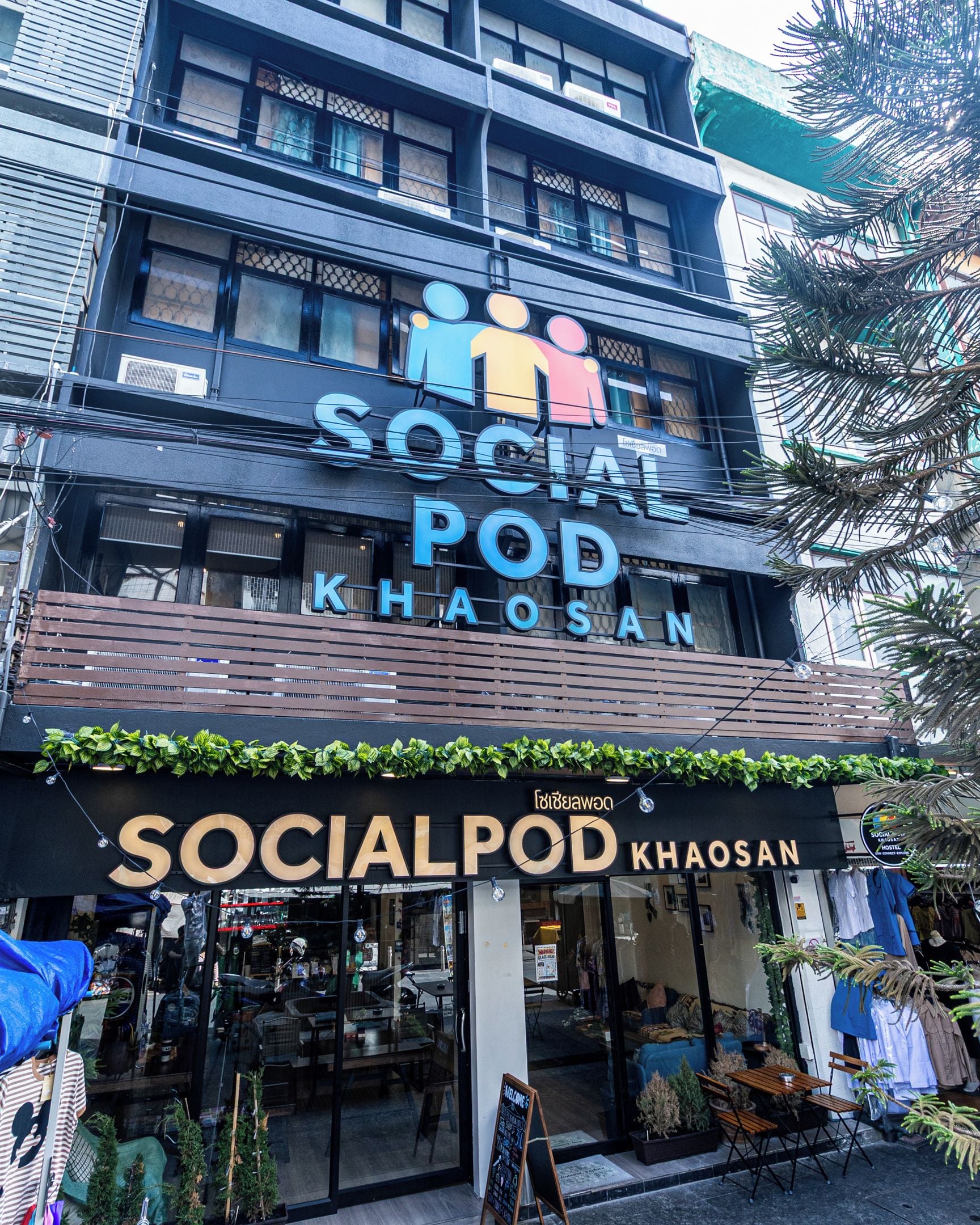 Un edificio con un letrero que dice 'SOCIAL POD KHAOSAN' y un escaparate con puertas de vidrio.