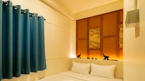 Une chambre d’hôtel avec un lit, des oreillers, un rideau et une œuvre d’art accrochée au mur.