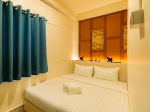 Ein Hotelzimmer mit einem Bett, Kissen, einem Vorhang und einem an der Wand hängenden Kunstwerk.