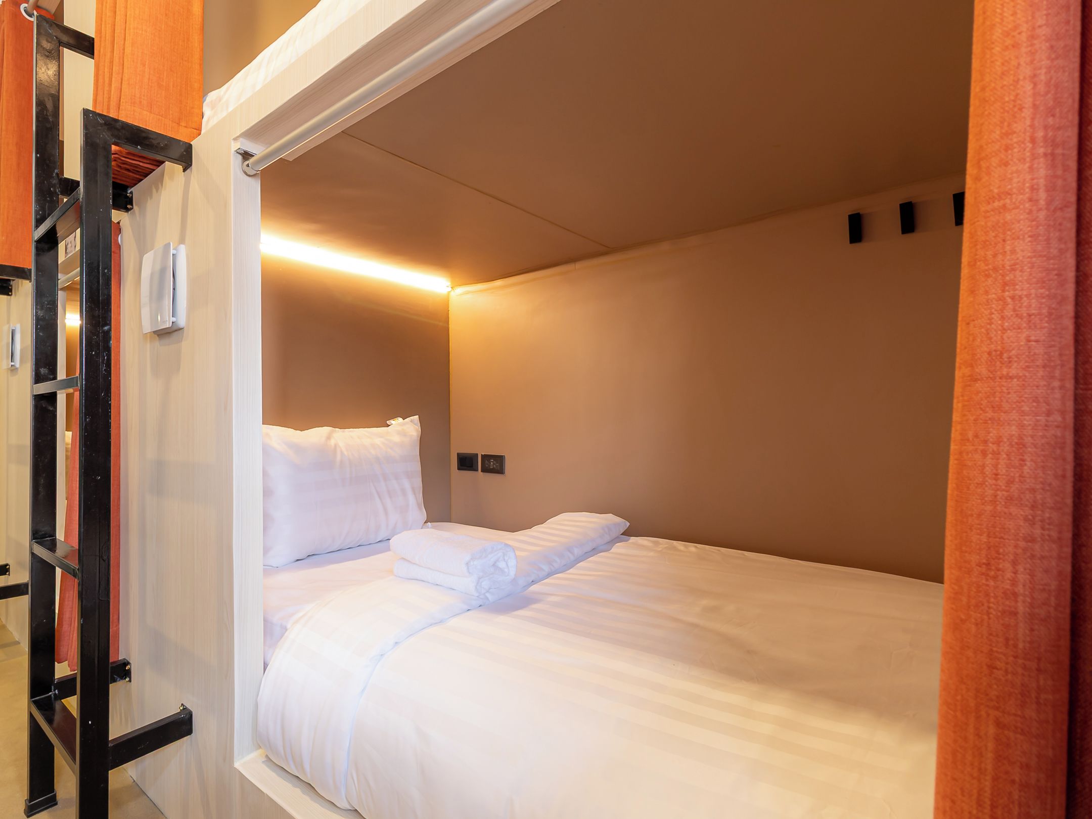 A single bed with white bedding in a room with beige walls and a wooden door frame.
