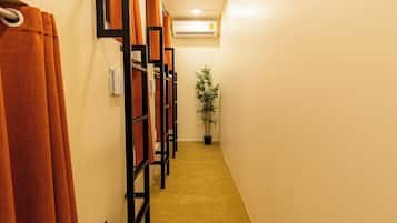 A hallway with a row of wooden lockers, a potted plant, and a wall-mounted air conditioning unit.