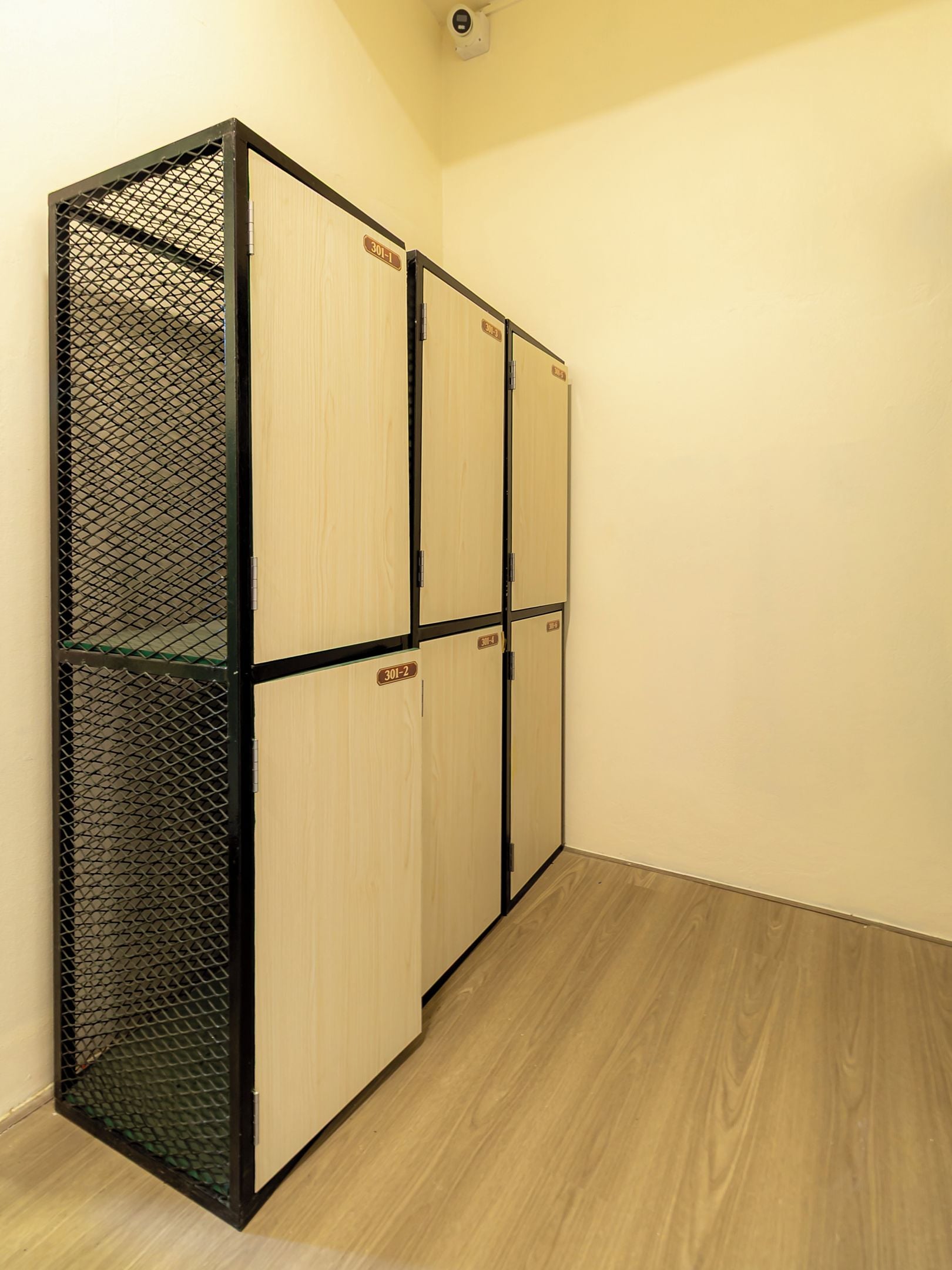 A hallway with a wooden floor and a metal partition with numbered doors.