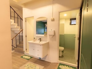 A bathroom with a toilet, a sink, and a mirror. - Social Pod Khao San Hostel (Bangkok)