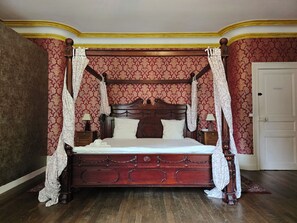 Ein Himmelsbett mit Holzrahmen, zwei Nachttische und ein Beistelltisch.