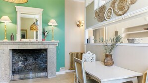 A dining area with a white table and chairs, a fireplace, and decorative wall sconces. - Château de l'Isle Marie (Picauville)