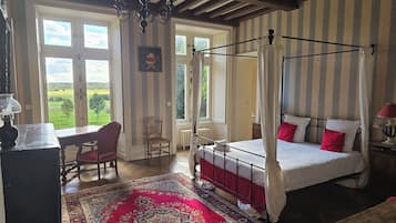 Une chambre à coucher avec un lit à baldaquin, un bureau avec une chaise et une grande fenêtre.