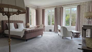 A hotel room with a bed, a chair, a table, and large windows.