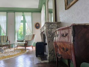 Una habitación con chimenea, cómoda de madera, una silla y una mesa.