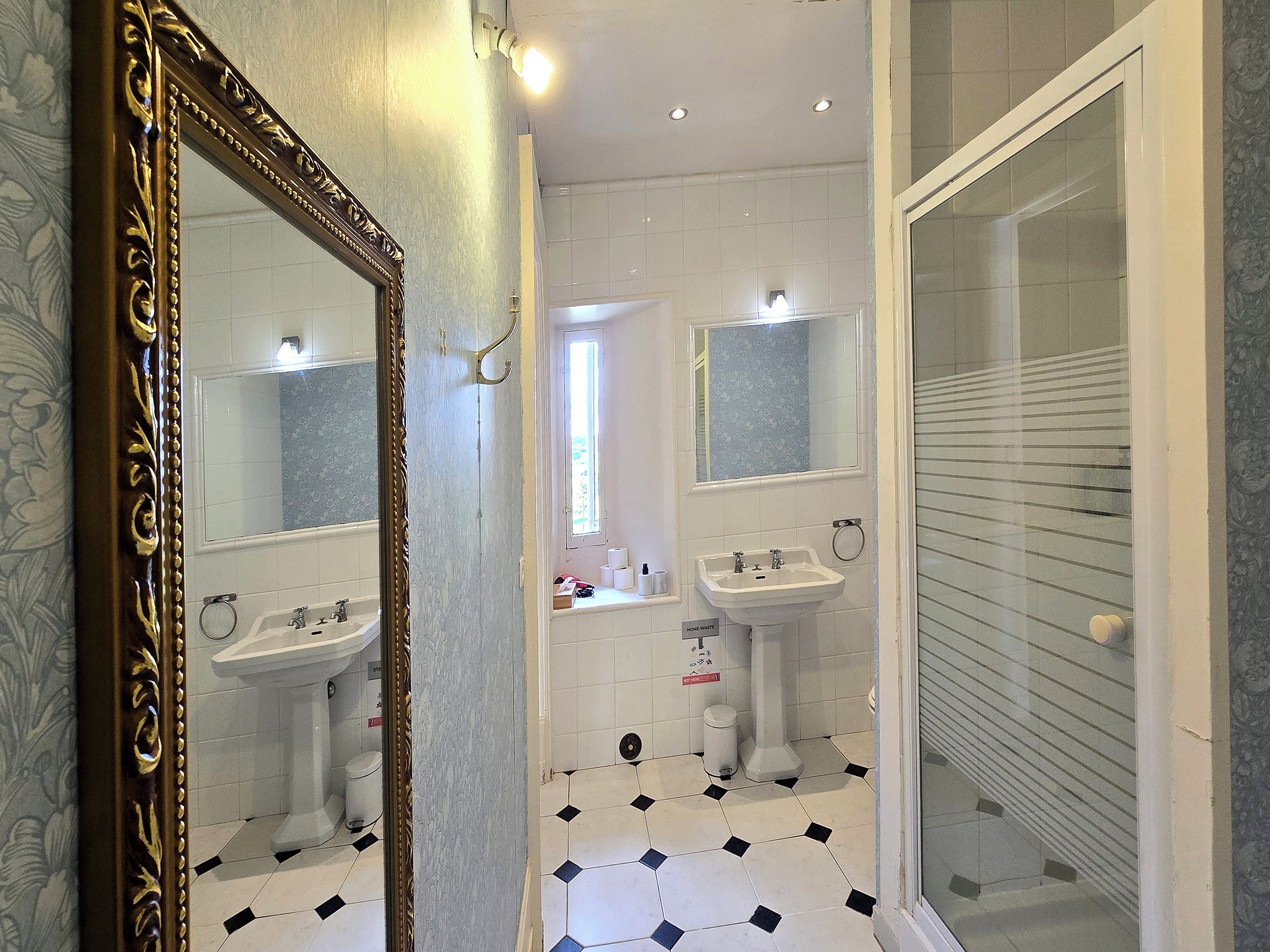 Ein Badezimmer mit großem Spiegel, zwei Waschbecken, einer Dusche und einer Toilette.