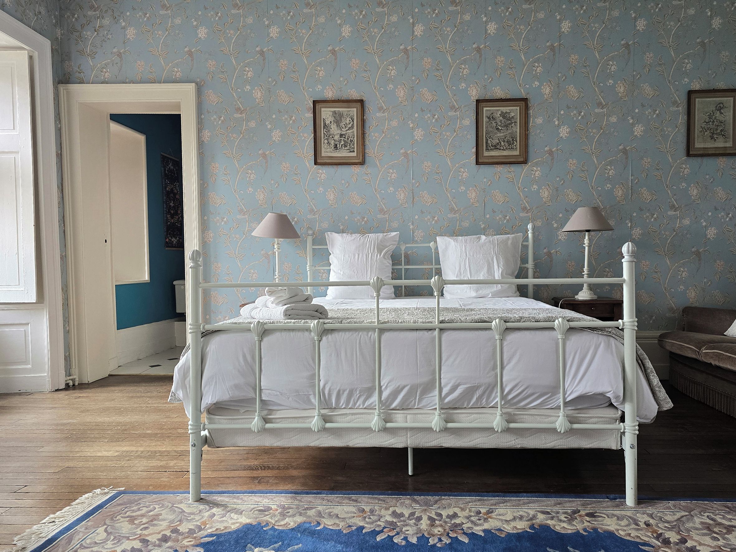 Una camera da letto con un letto in metallo bianco, biancheria da letto bianca e due lampade a parete.