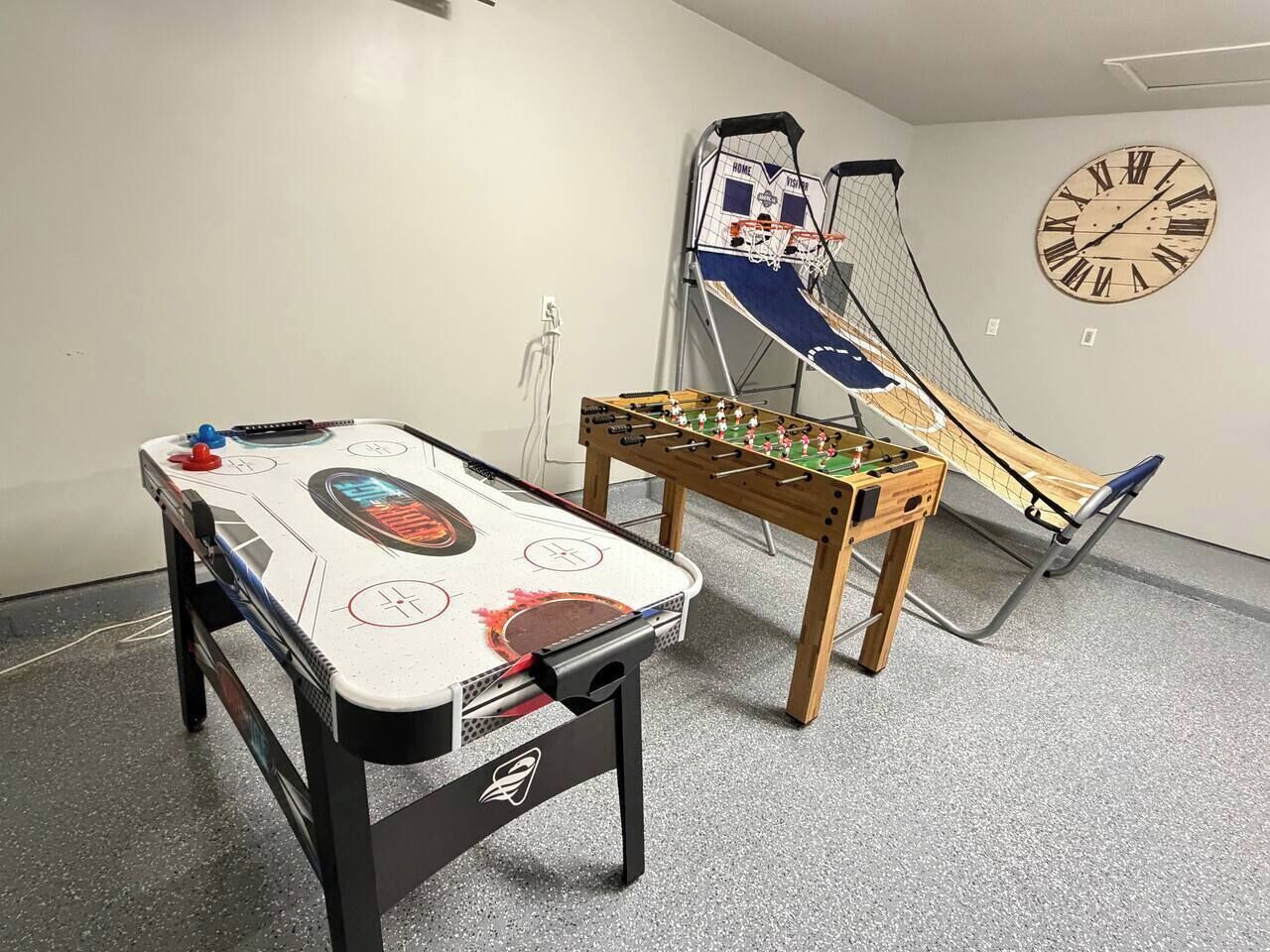 Une pièce équipée d’un baby-foot, d’un jeu de hockey sur table et d’un panier de basket.