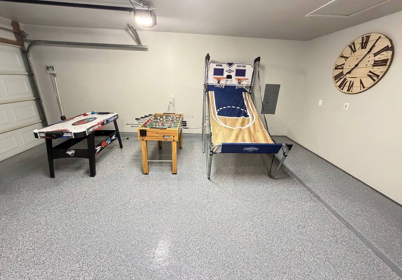 A room with a foosball table, a small table, and a bed with a headboard.