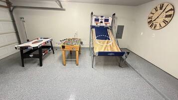A room with a foosball table, a small table, and a bed with a headboard.