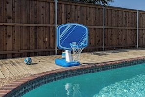 A swimming pool with a blue basketball hoop and a wooden deck. - Family 3BR Gem with Private Pool & Game Room (Flower Mound)