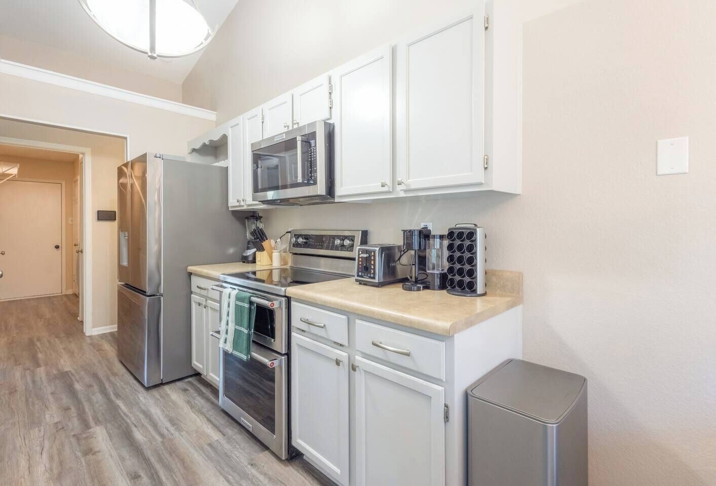 A modern kitchen with stainless steel appliances, white cabinetry, and a built-in microwave.