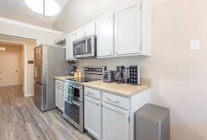 A modern kitchen with stainless steel appliances, white cabinetry, and a built-in microwave. - Family 3BR Gem with Private Pool & Game Room (Flower Mound)