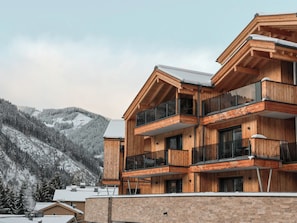 Un edificio de madera de varios pisos con balcones, con una montaña nevada al fondo.