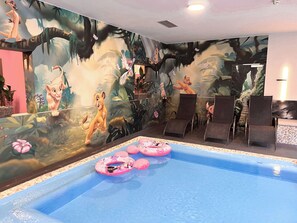 Una piscina interior con un mural de personajes animados en las paredes.