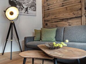 Ein Zimmer mit einer Couch, einem Couchtisch, einer Stehlampe und einem Wandbild.