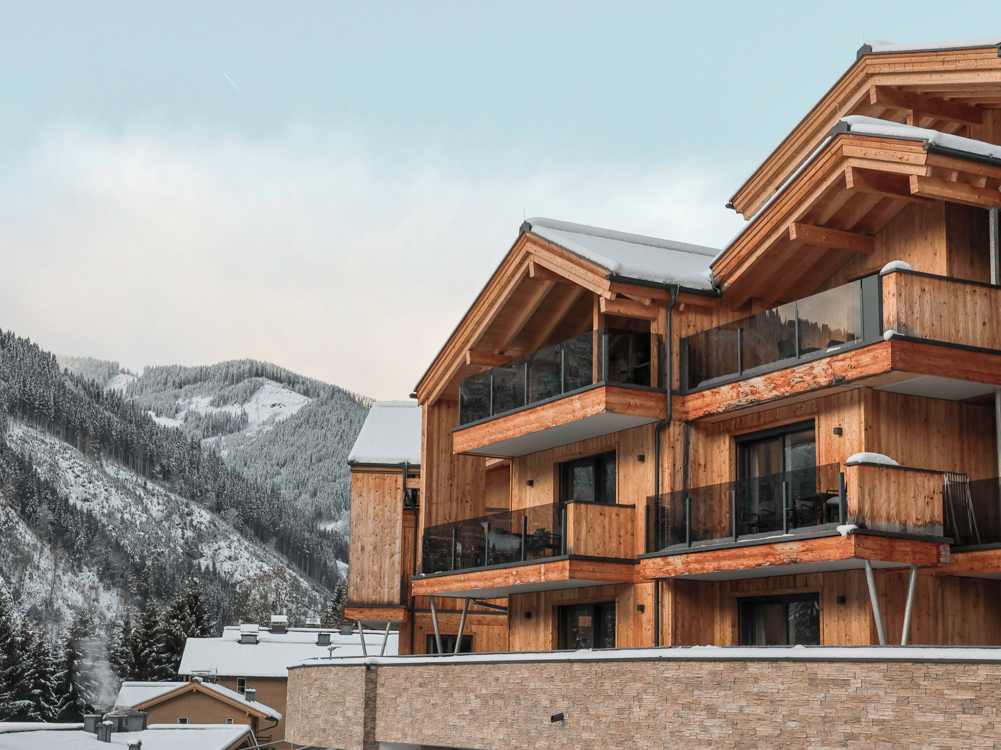 Un edificio de madera de varios pisos con balcones, con una montaña nevada al fondo.