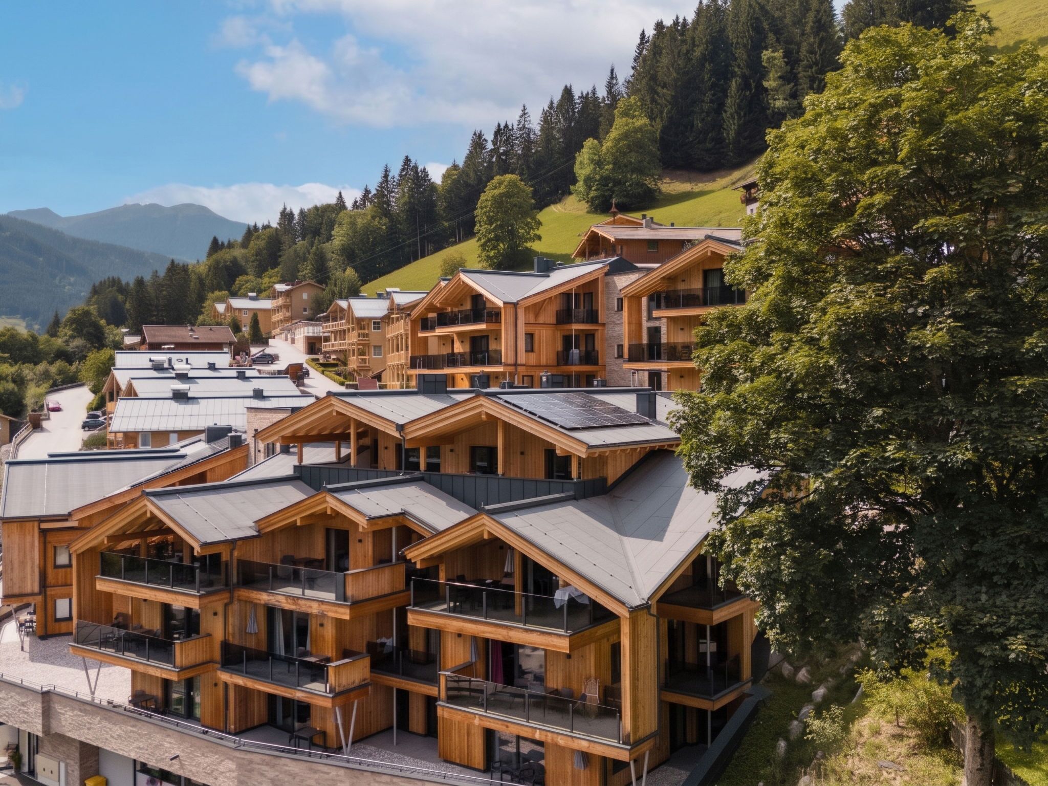 Eine Gruppe von Holzhäusern im Chalet-Stil mit Balkonen, vor dem Hintergrund grüner Hügel und eines klaren Himmels.