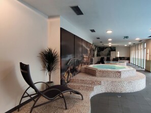 Ein Wellnessbereich mit Whirlpool, Sitzgelegenheiten und einem Wandgemälde.