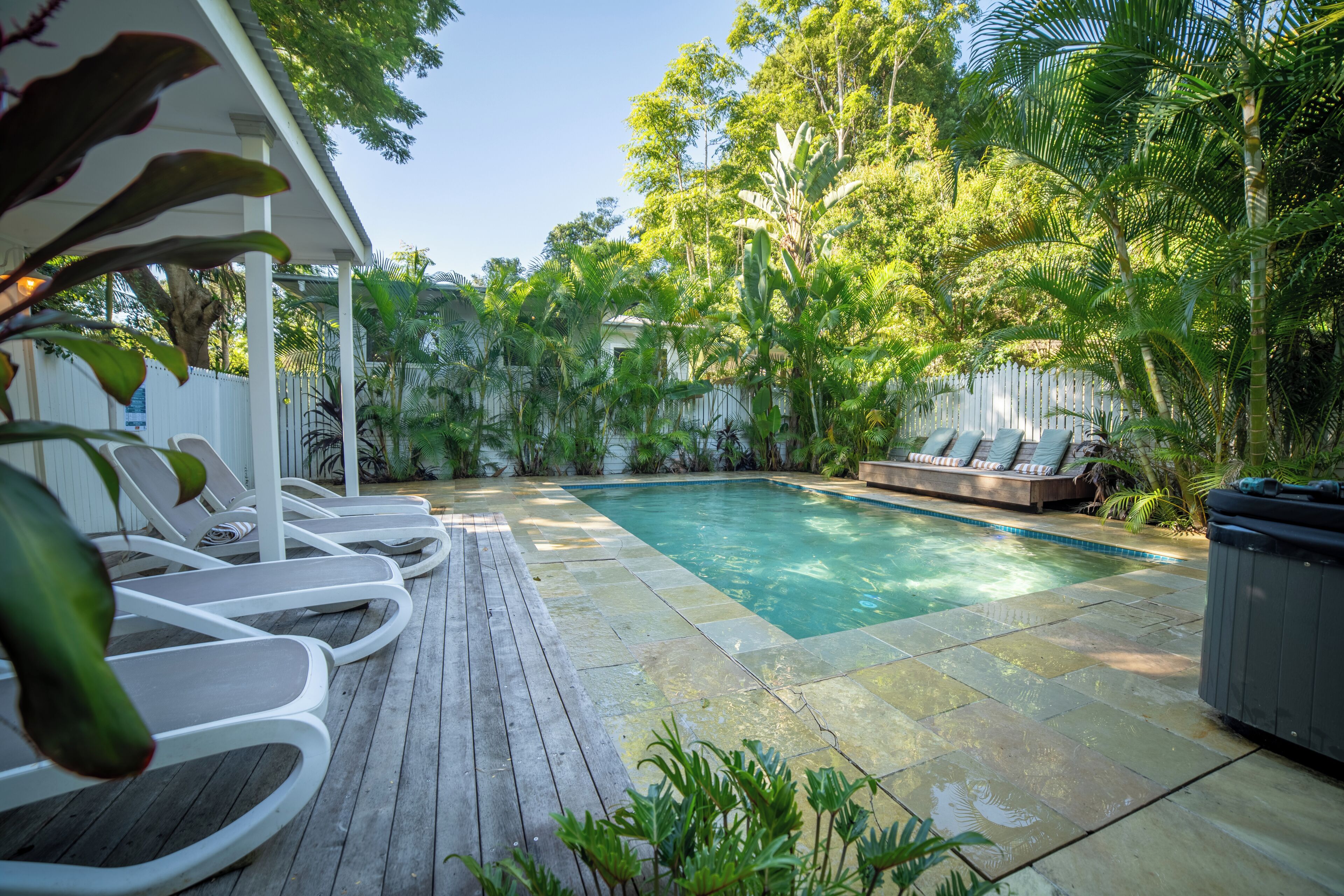 A pool area with lounge chairs and a hot tub.