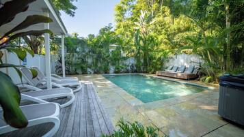 A pool area with lounge chairs and a hot tub.