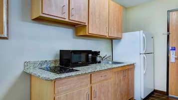 A compact kitchen with wooden cabinets, a microwave, a stove, and a refrigerator.