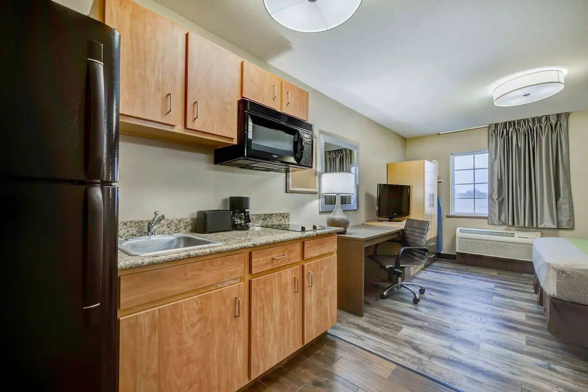 A compact kitchen with a refrigerator, microwave, and sink.