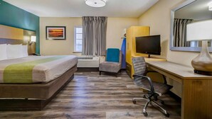 A hotel room with a bed, desk, chair, television, and a large mirror. - 1 King Bed Unit w/ Kitchenette & Free Parking | Oak Park Mall - 2.4 miles (Johnson County)