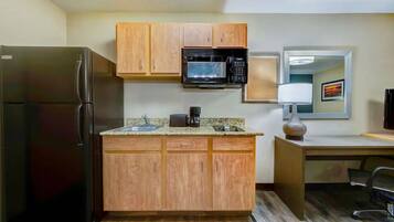 A compact kitchen with a refrigerator, microwave, and wooden cabinets.