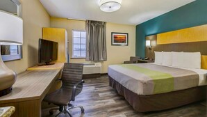 A hotel room with a bed, desk, chair, television, and a window with curtains. - Extended Stay Studio w/ Kitchenette | Town Center Plaza - 6.7 miles (Johnson County)
