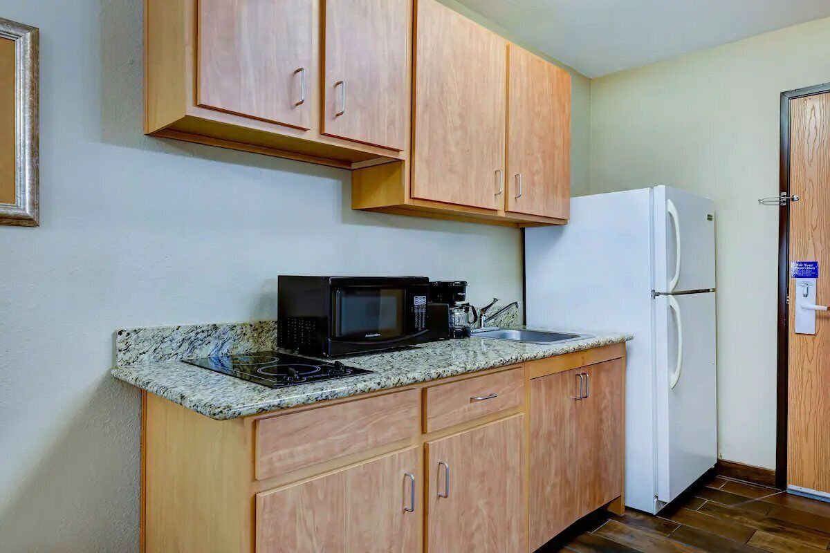 A compact kitchen with wooden cabinets, a microwave, a stove, and a refrigerator.