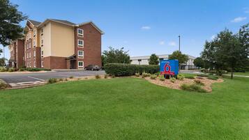A hotel with a brick facade, a parking lot, and a sign indicating extended stay availability.