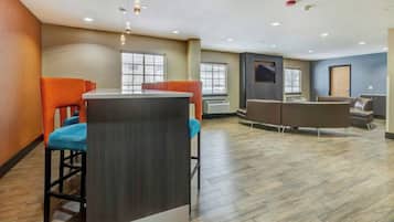 A modern indoor space with a bar area, seating, and a flat-screen TV mounted on the wall.