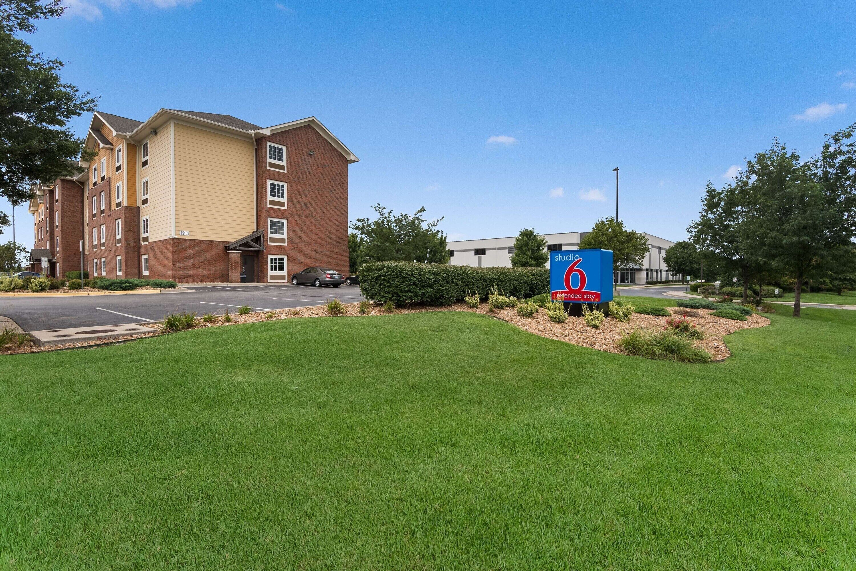 A hotel with a brick facade, a parking lot, and a sign indicating extended stay availability.
