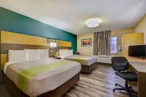Hotellihuone, jossa on kaksi sänkyä, työpöytä tuolilla, televisio ja ikkuna, jossa on verhot.