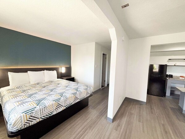 Una habitación de hotel moderna con una cama grande, un escritorio y una kitchenette.