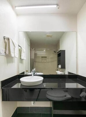 Un baño con un espejo grande, un lavamanos y un inodoro.