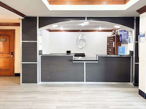 A reception desk with a digital screen, a large number '6' sign, and a security camera above. - Enjoy Affordable Comfort | 2 Units in Central Irving | Pet-Friendly Stay (Irving)