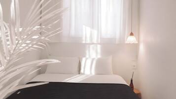 A bed with white bedding, a dark headboard, and a bedside table with a lamp.