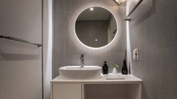 A modern bathroom with a round mirror, a white sink, and a towel rack.
