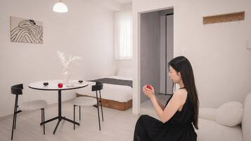 A modern living room with a sofa, a dining table with chairs, and a minimalist decor.