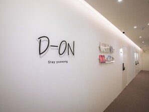 Un pasillo con un letrero que dice 'D-ON Stay yuseong' y una hilera de estanterías llenas de libros y revistas.