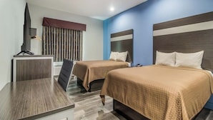 Ein Hotelzimmer mit zwei Betten, einem Schreibtisch und einem Fernseher.