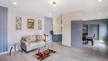 Una sala de estar moderna con sofá, mesa de centro de vidrio y decoración en la pared.