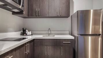 Una cocina moderna con alacenas de madera oscura, un refrigerador de acero inoxidable y un microondas integrado.