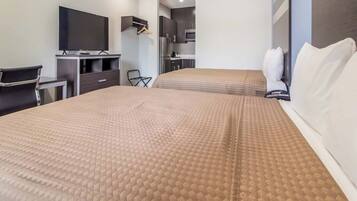 Una habitación de hotel con cama, televisión, escritorio y kitchenette.
