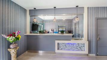 Un área de recepción de diseño moderno, con un mostrador de recepción, un jarrón decorativo con flores y una pared acentuada con azulejos.